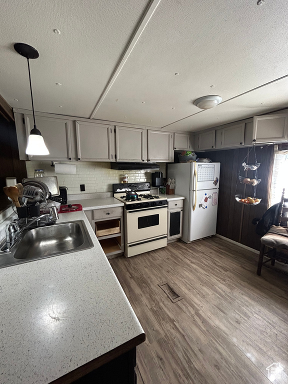 Kitchen with gray cabinets, dark wood-type flooring, sink, white appliances, and decorative light fixtures