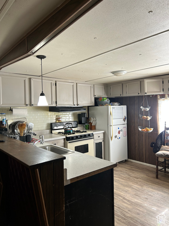 Kitchen featuring pendant lighting, white appliances, light hardwood / wood-style flooring, backsplash, and extractor fan