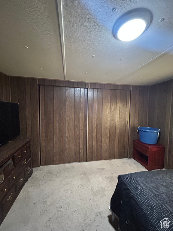 Bedroom featuring a textured ceiling and wood walls