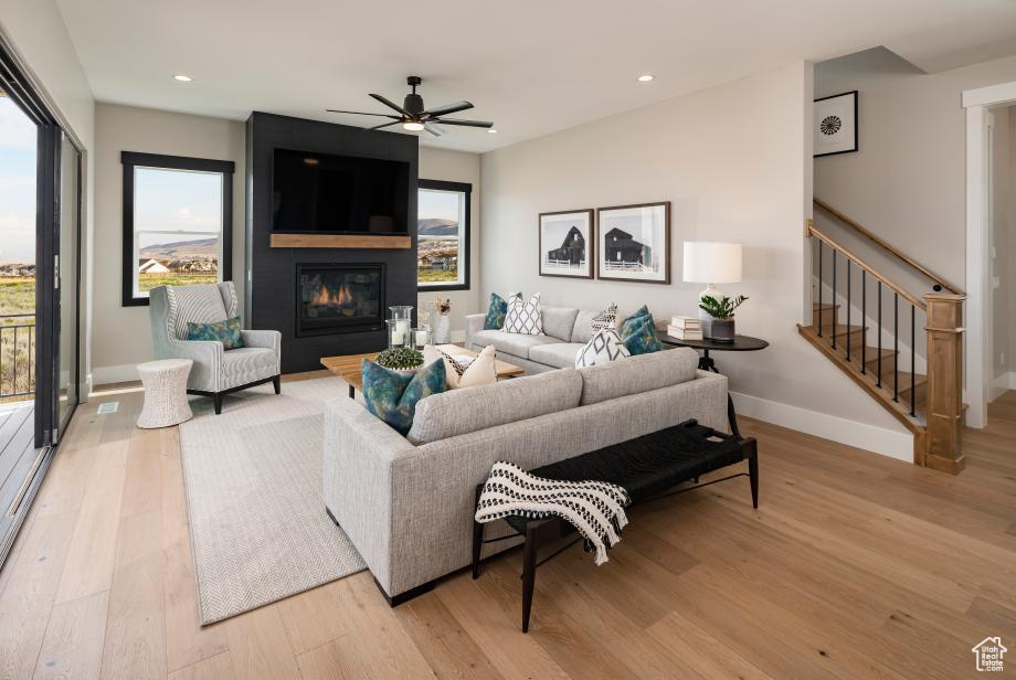 Living room with light hardwood / wood-style floors, ceiling fan, and a fireplace