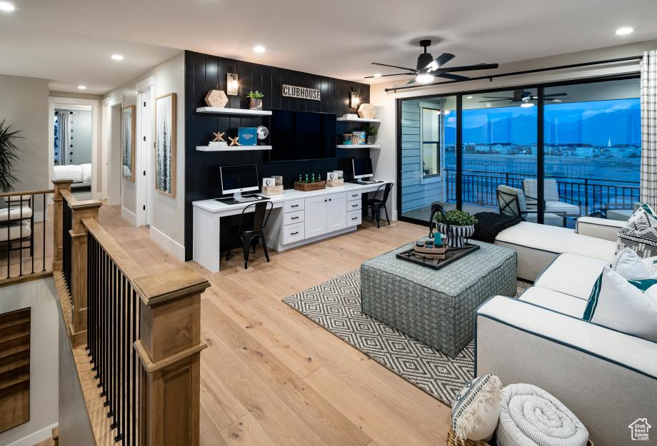 Living room with light hardwood / wood-style flooring, built in desk, and ceiling fan