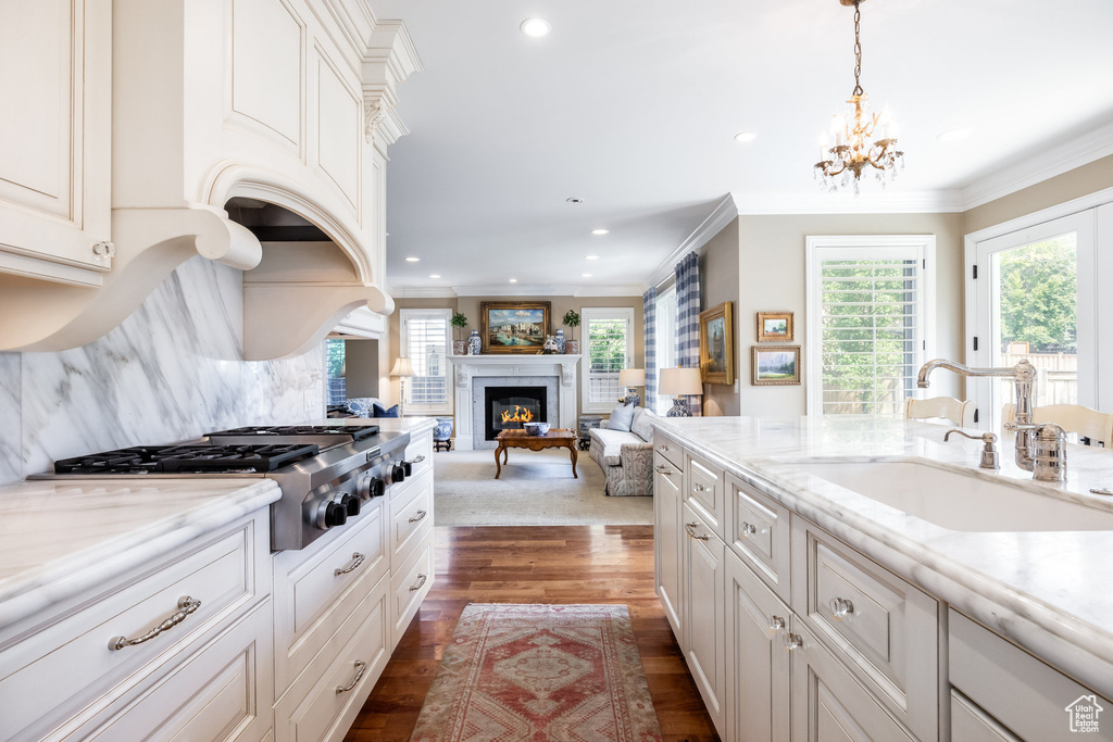 Kitchen featuring white cabinets, a fireplace, dark hardwood / wood-style flooring, pendant lighting, and sink