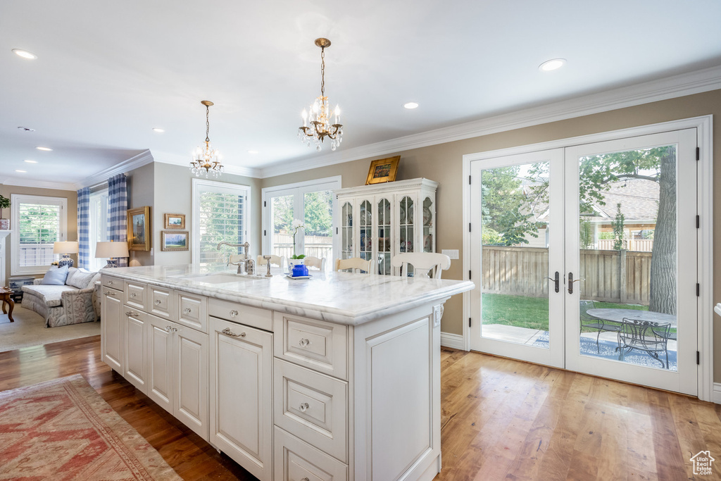 Kitchen featuring decorative light fixtures, an island with sink, and plenty of natural light