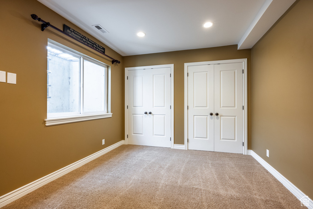 Unfurnished bedroom with carpet flooring and multiple closets