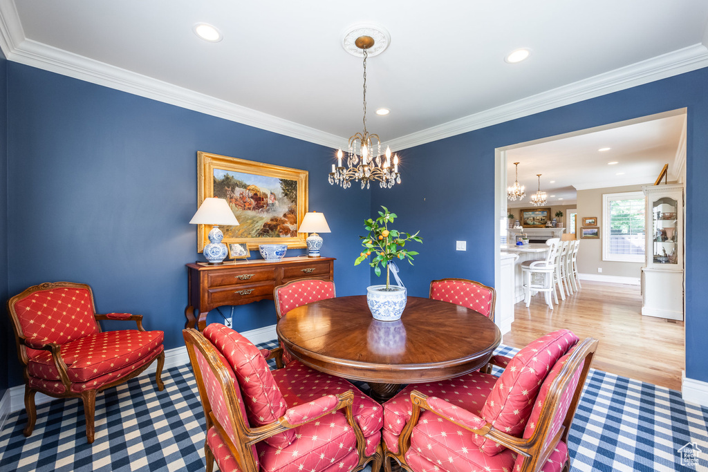 Dining room featuring a notable chandelier, light hardwood / wood-style flooring, and ornamental molding