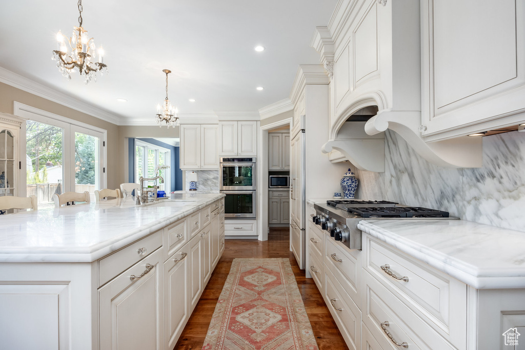 Kitchen with appliances with stainless steel finishes, a large island with sink, dark hardwood / wood-style flooring, and decorative backsplash