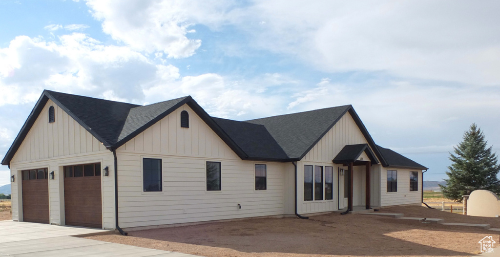 Modern farmhouse style home with board and batten siding, concrete driveway, a garage, and roof with shingles