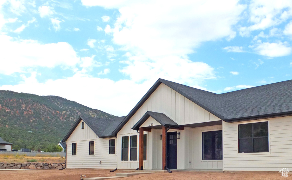 Modern farmhouse style home featuring a mountain view, board and batten siding, and roof with shingles