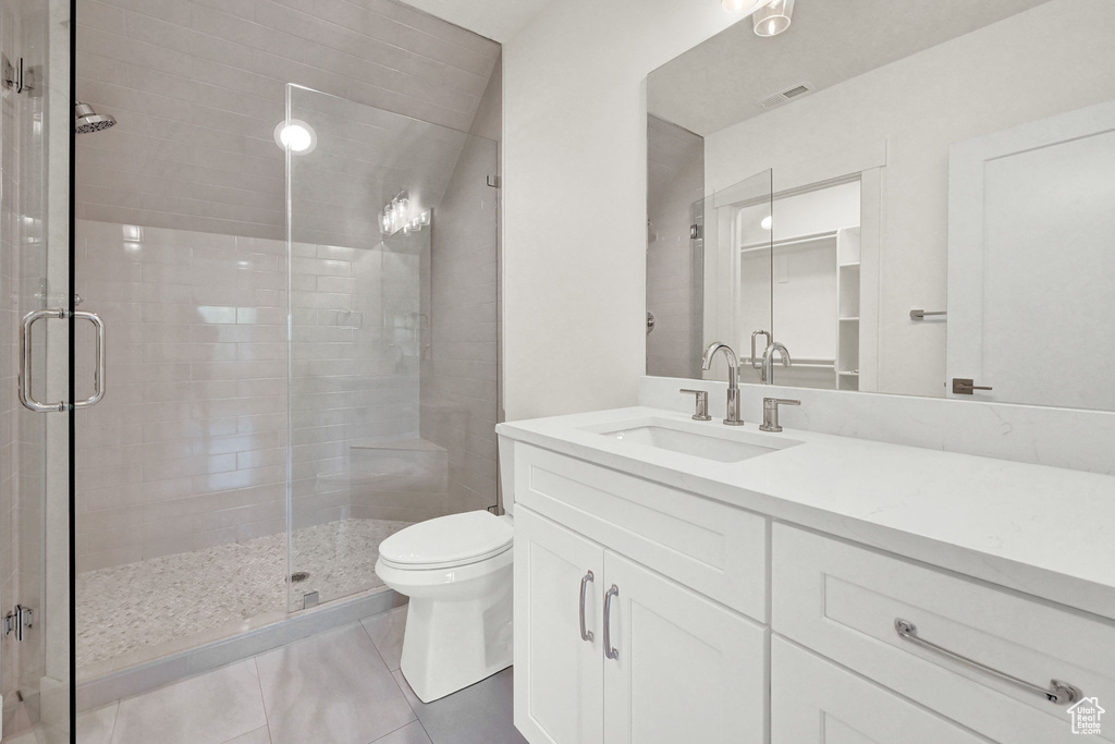 Bathroom featuring vanity, a shower with shower door, toilet, and tile patterned flooring