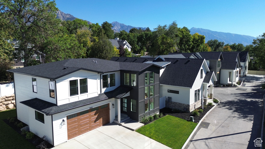 View of front of house with a mountain view, a garage, and a front lawn