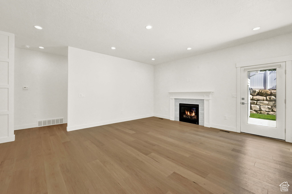 Unfurnished living room featuring hardwood / wood-style floors, a textured ceiling, and a fireplace