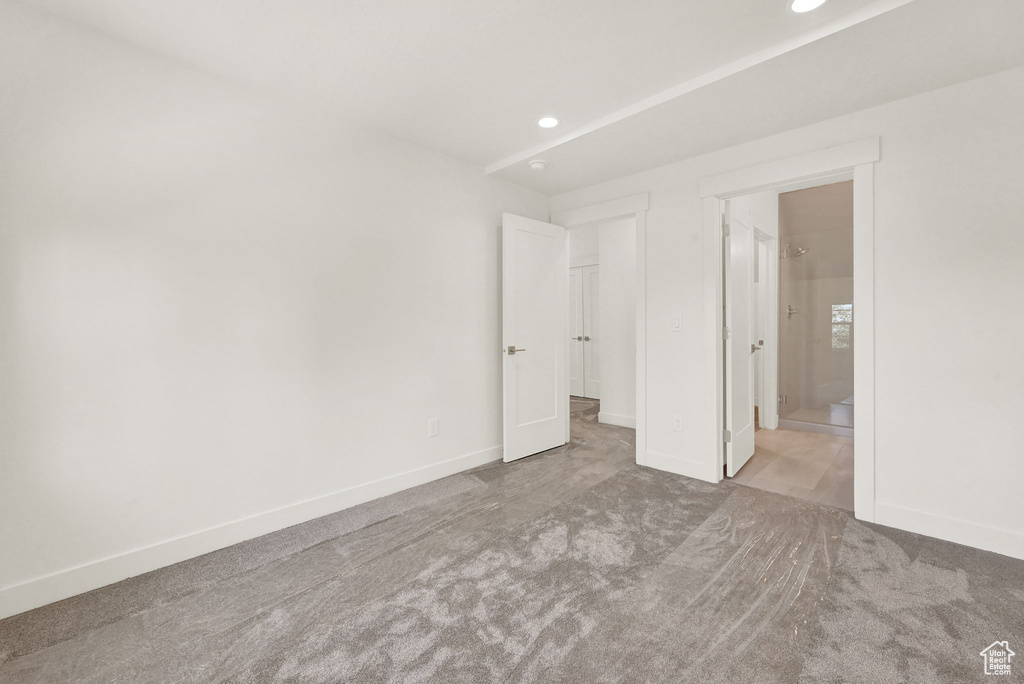 Unfurnished bedroom featuring ensuite bath and light carpet