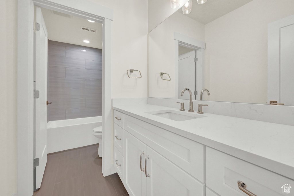 Full bathroom with tiled shower / bath combo, vanity, and toilet