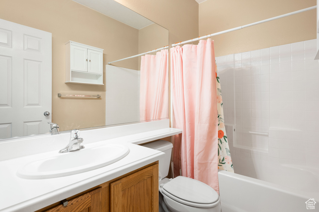 Full bathroom featuring vanity, toilet, and shower / bathtub combination with curtain