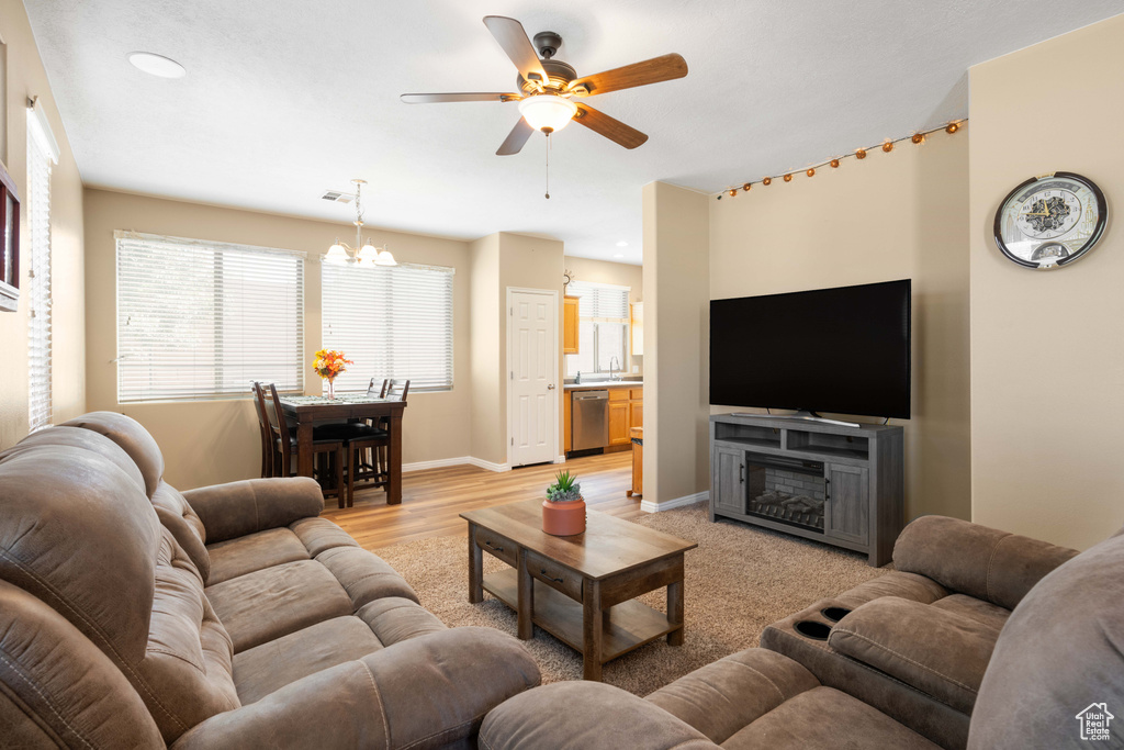 Living room with sink, ceiling fan with notable chandelier, and light hardwood / wood-style floors