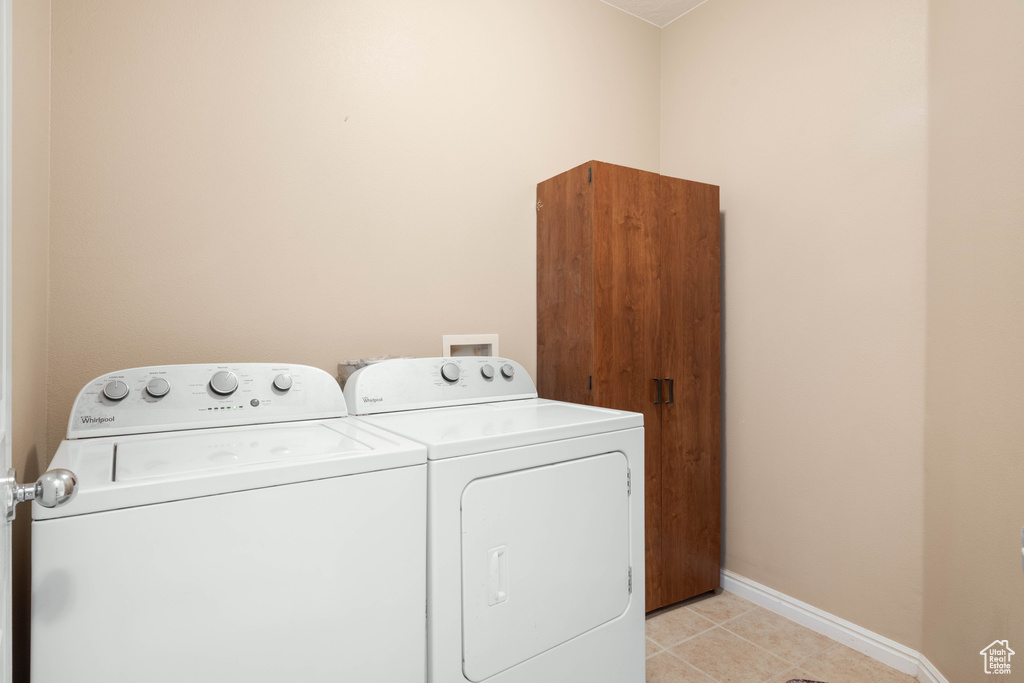 Laundry area featuring washing machine and dryer and light tile patterned floors