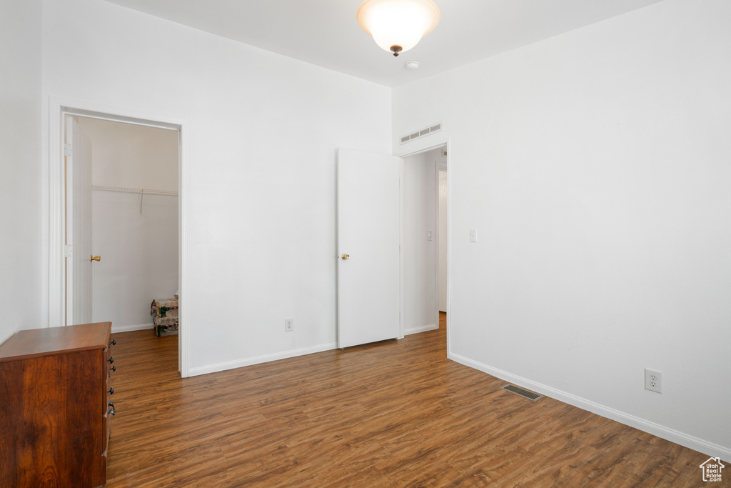 Unfurnished bedroom with a closet, a walk in closet, and hardwood / wood-style floors