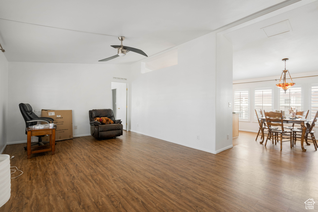 Sitting room featuring ceiling fan with notable chandelier and dark hardwood / wood-style floors