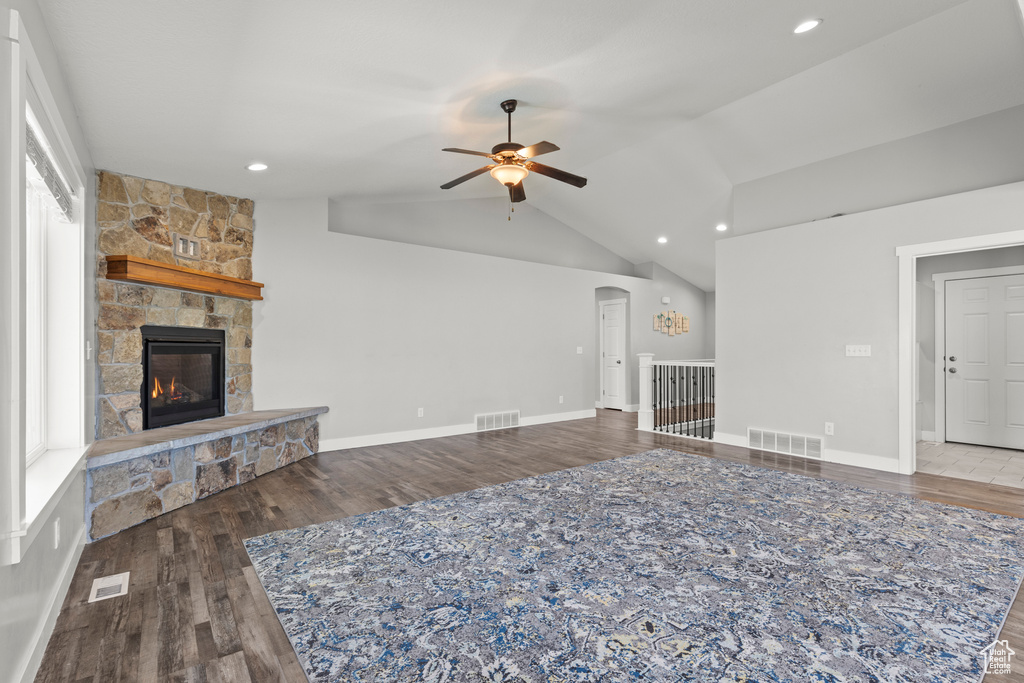 Unfurnished living room featuring wood finished floors, ceiling fan, a stone fireplace, lofted ceiling, and recessed lighting
