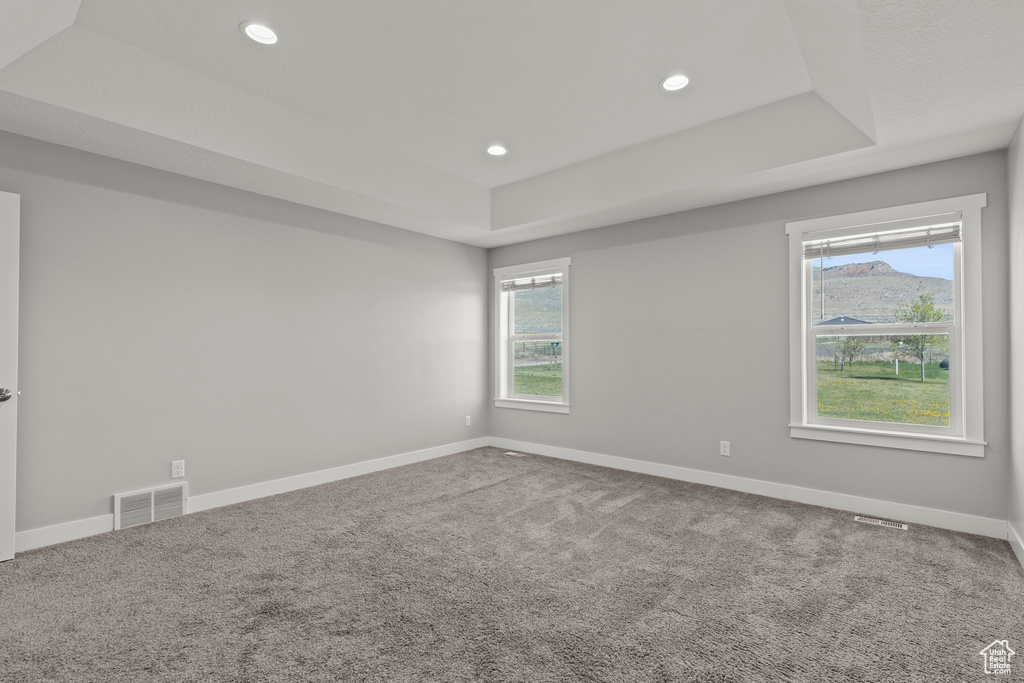 Empty room featuring a tray ceiling, baseboards, carpet flooring, and recessed lighting