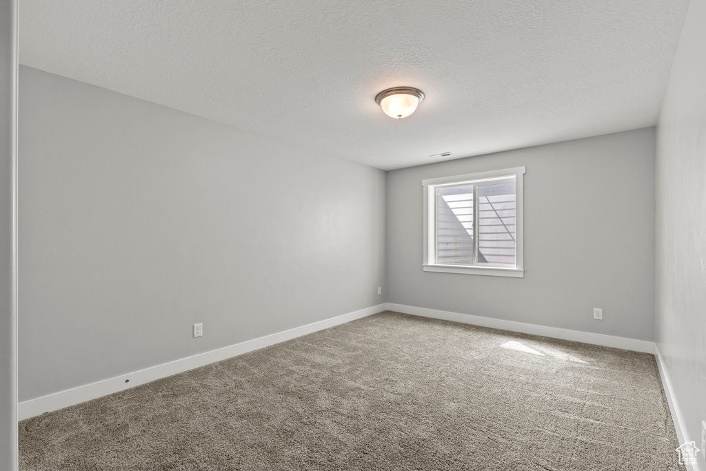 Unfurnished room with carpet floors, a textured ceiling, and baseboards