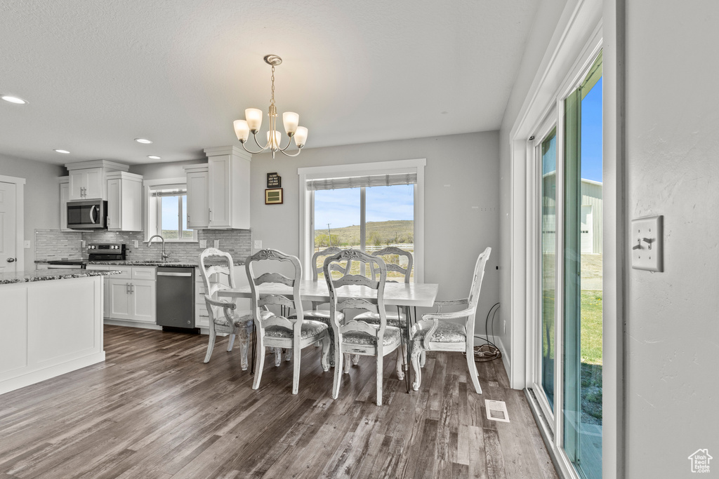 Dining area featuring dark wood-style floors, a chandelier, and recessed lighting