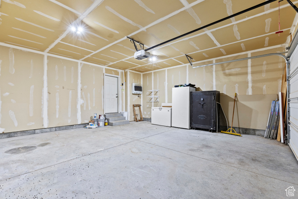Garage featuring white fridge, a garage door opener, and refrigerator