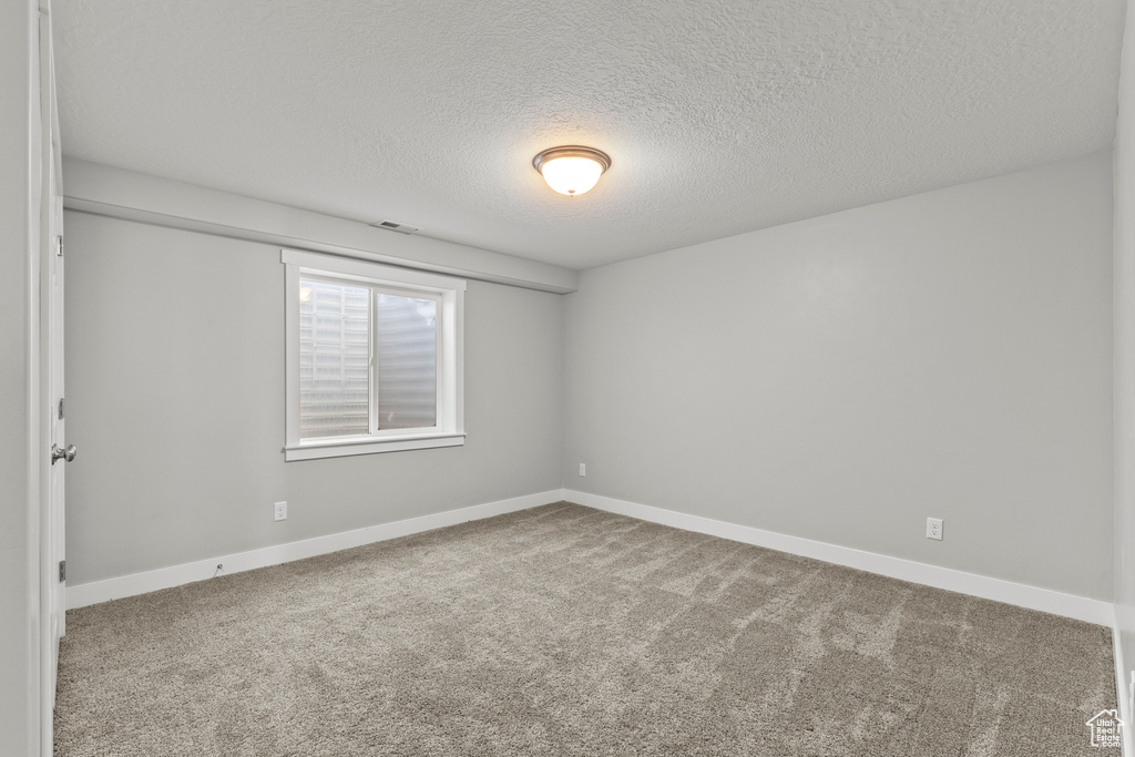 Unfurnished room with a textured ceiling, carpet flooring, and baseboards