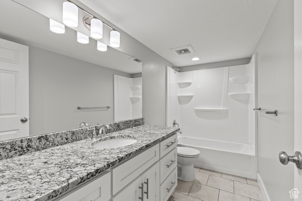 Bathroom with tile patterned flooring, vanity, toilet, shower / tub combination, and baseboards