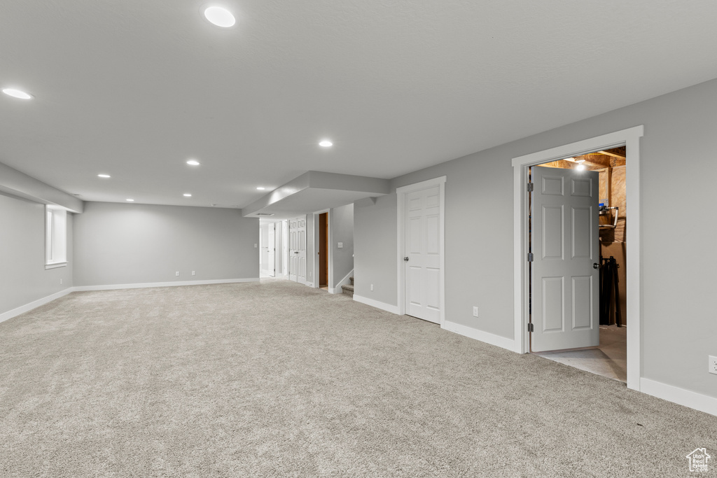 Finished basement featuring light carpet, recessed lighting, stairs, and baseboards