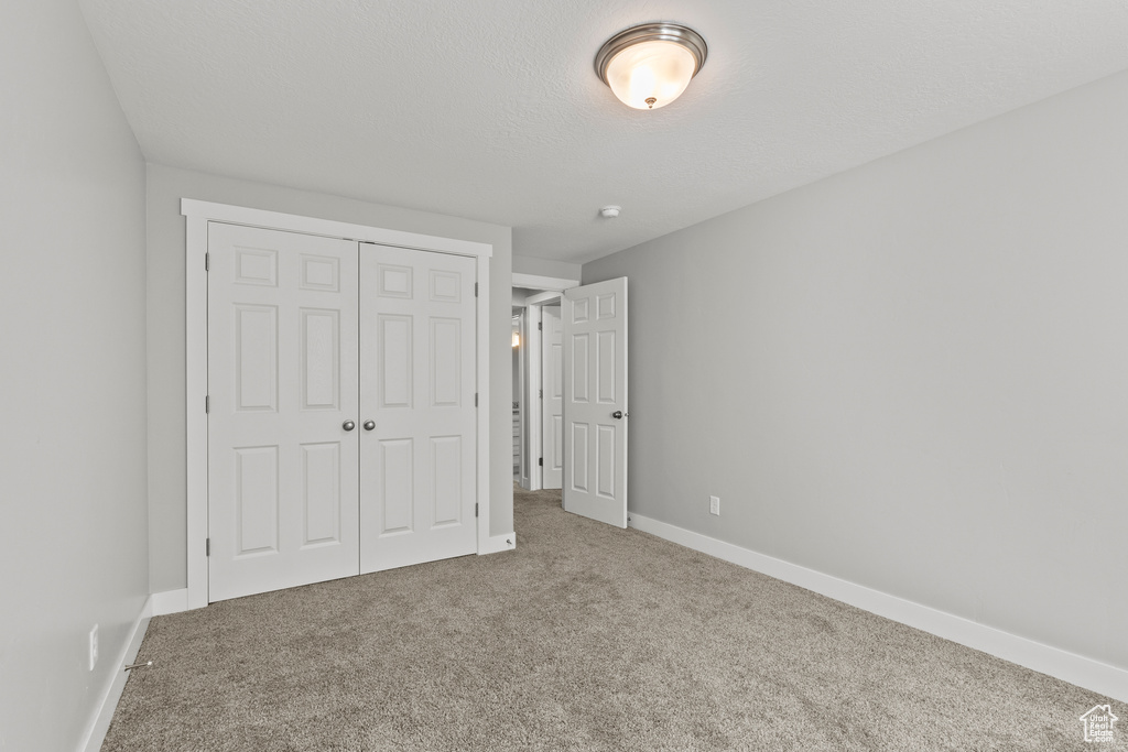 Unfurnished bedroom with carpet floors, a closet, and baseboards