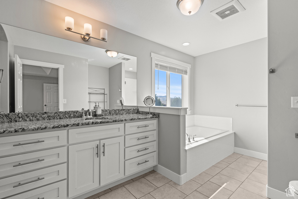 Bathroom with vanity, a bath, and baseboards