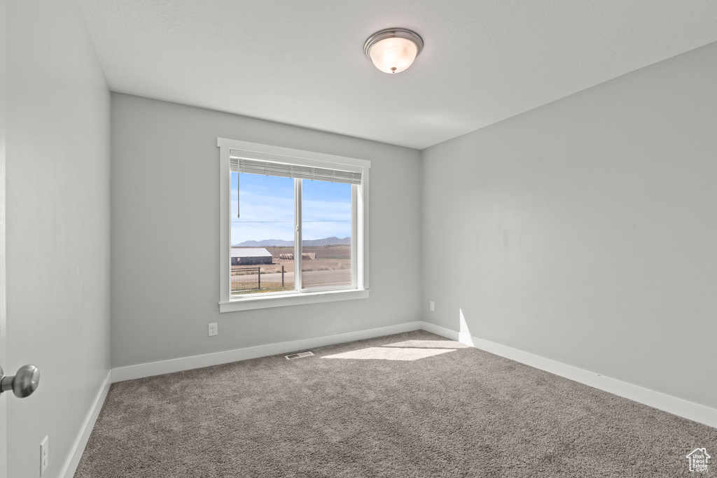 Empty room featuring carpet flooring and baseboards