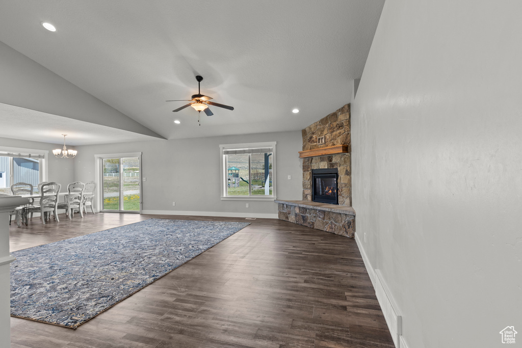 Living area featuring a fireplace, a ceiling fan, lofted ceiling, wood finished floors, and a chandelier