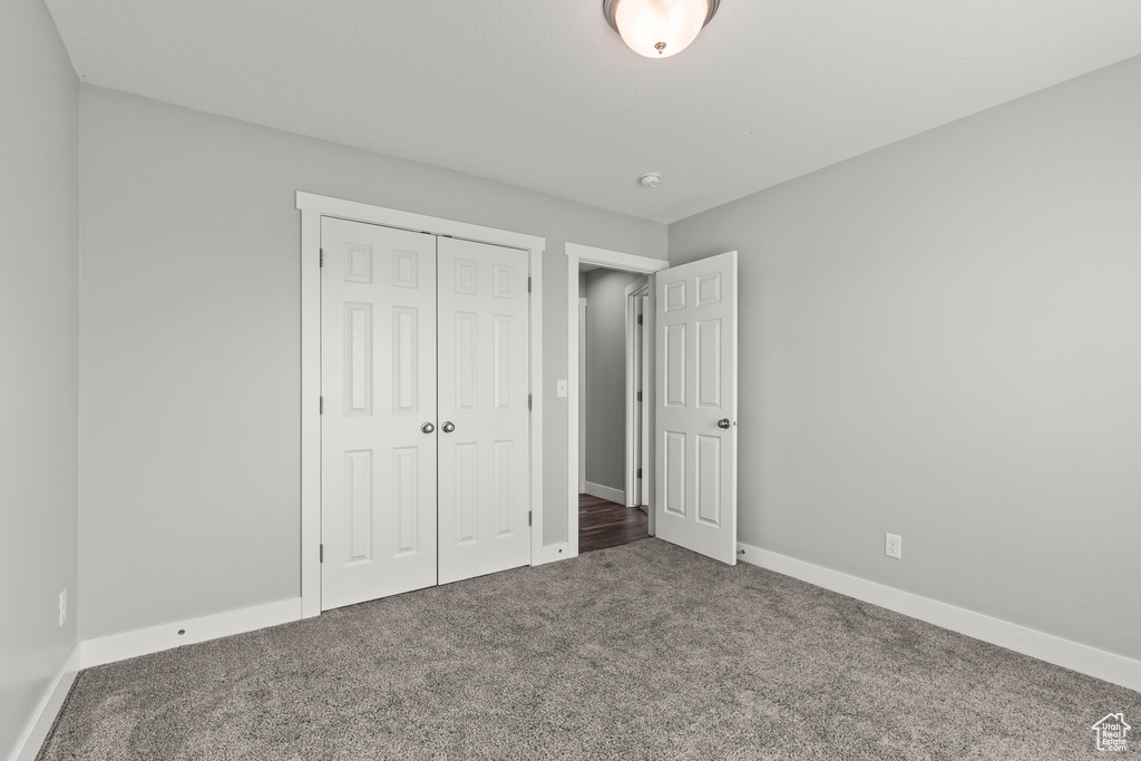 Unfurnished bedroom with carpet, a closet, and baseboards