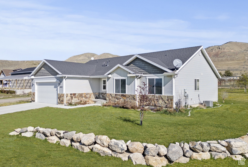 View of front of house with a garage, a front lawn, and stone siding