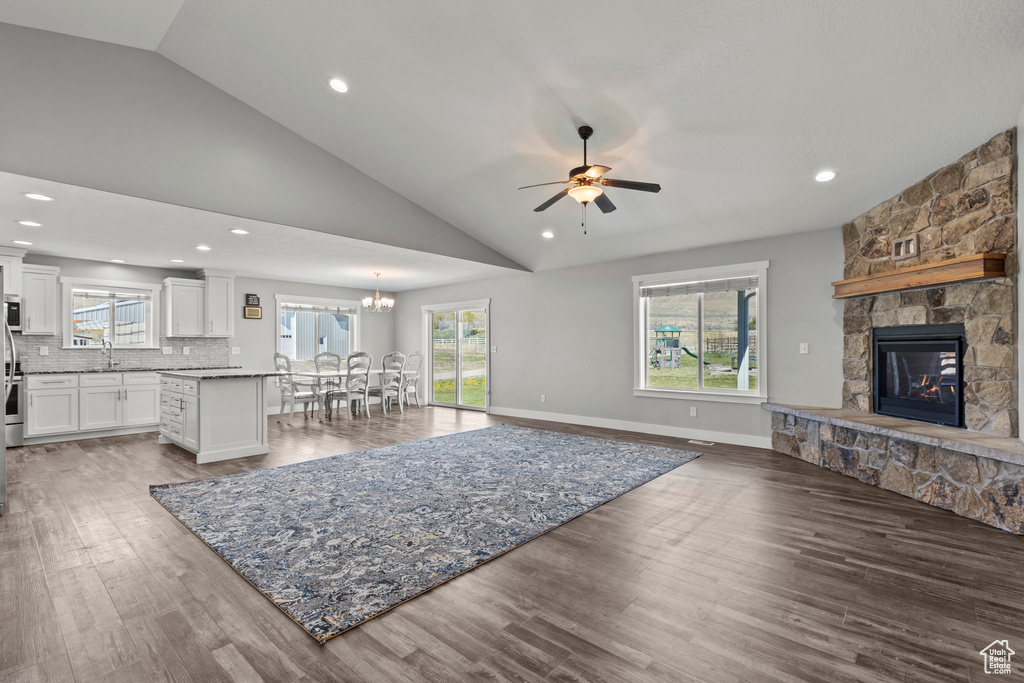 Living area featuring vaulted ceiling, wood finished floors, a ceiling fan, a fireplace, and recessed lighting