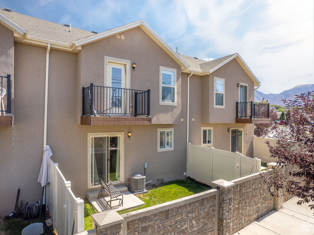 Back of property featuring a balcony, cooling unit, a mountain view, and a patio