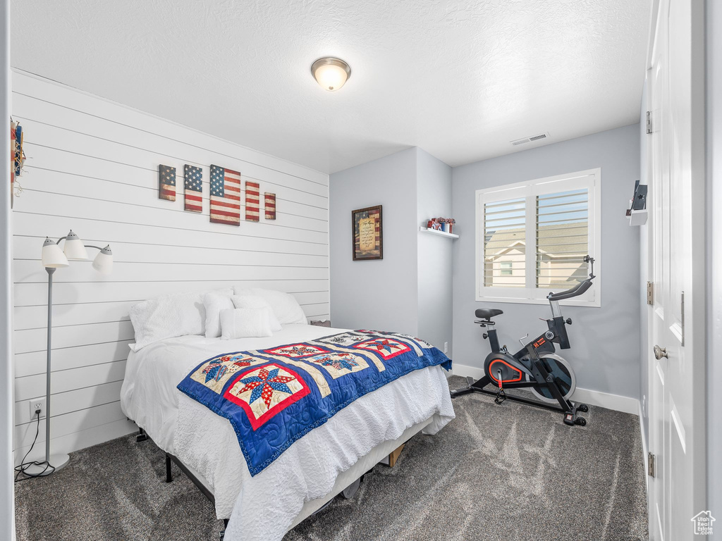 Carpeted bedroom featuring wood walls and a textured ceiling