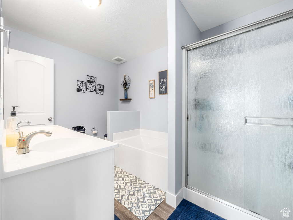 Bathroom with independent shower and bath, sink, and hardwood / wood-style flooring