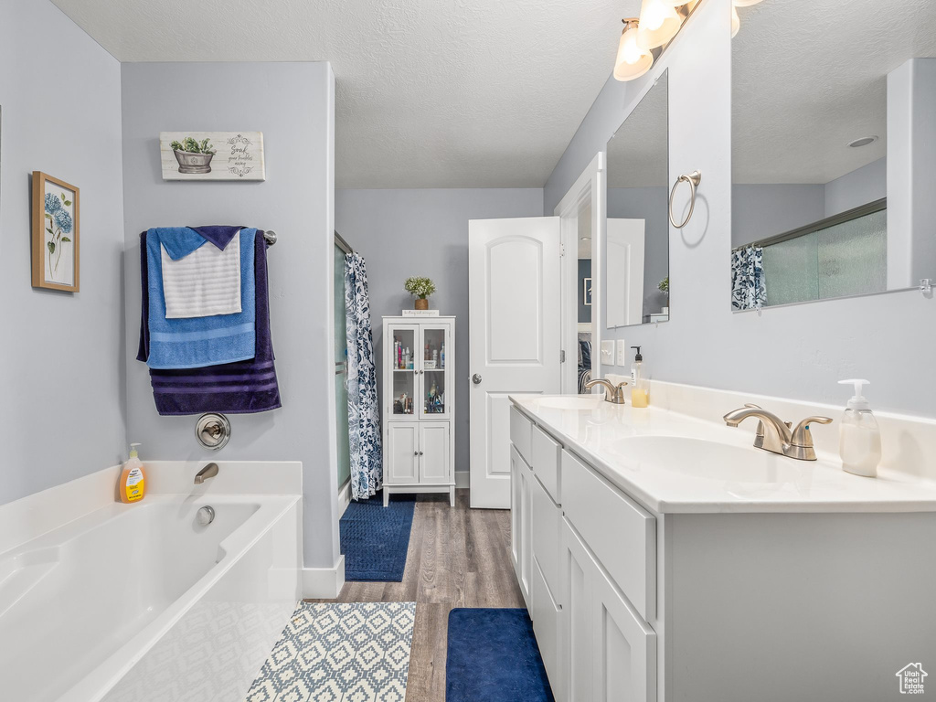 Bathroom featuring a textured ceiling, shower with separate bathtub, vanity, and hardwood / wood-style flooring