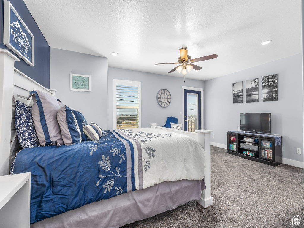 Bedroom featuring multiple windows, a textured ceiling, carpet flooring, and ceiling fan