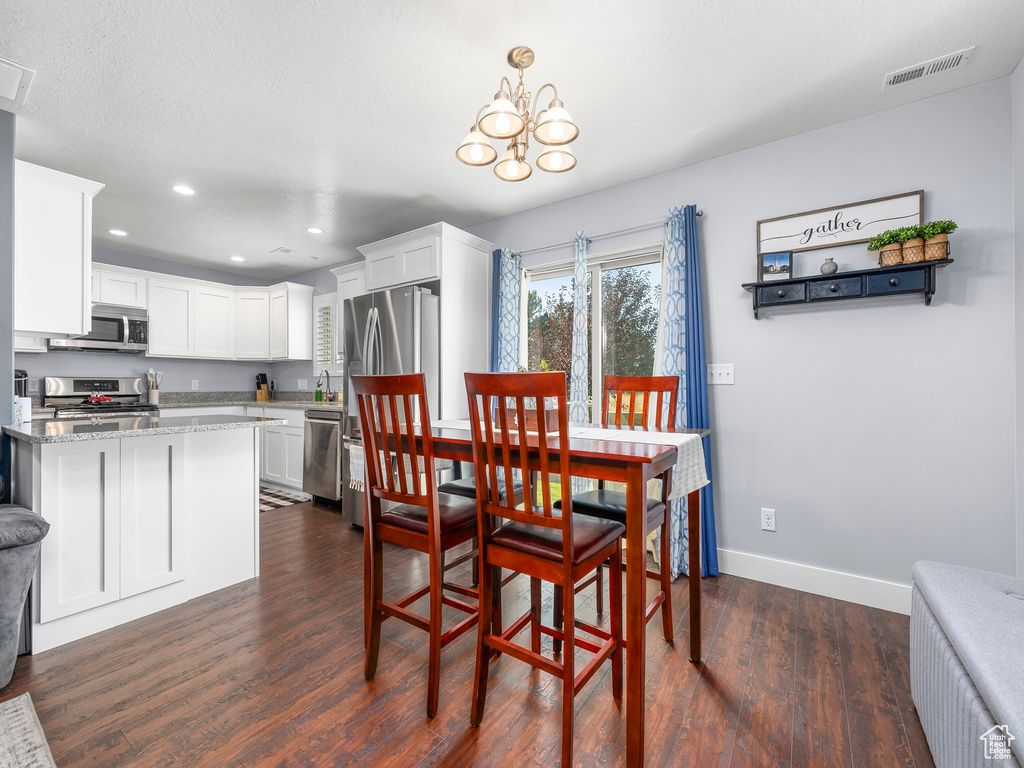 Dining room with a notable chandelier, a textured ceiling, and dark wood-type flooring