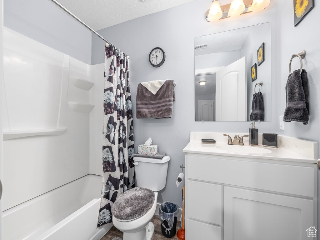 Full bathroom featuring shower / bath combo, a textured ceiling, vanity, and toilet