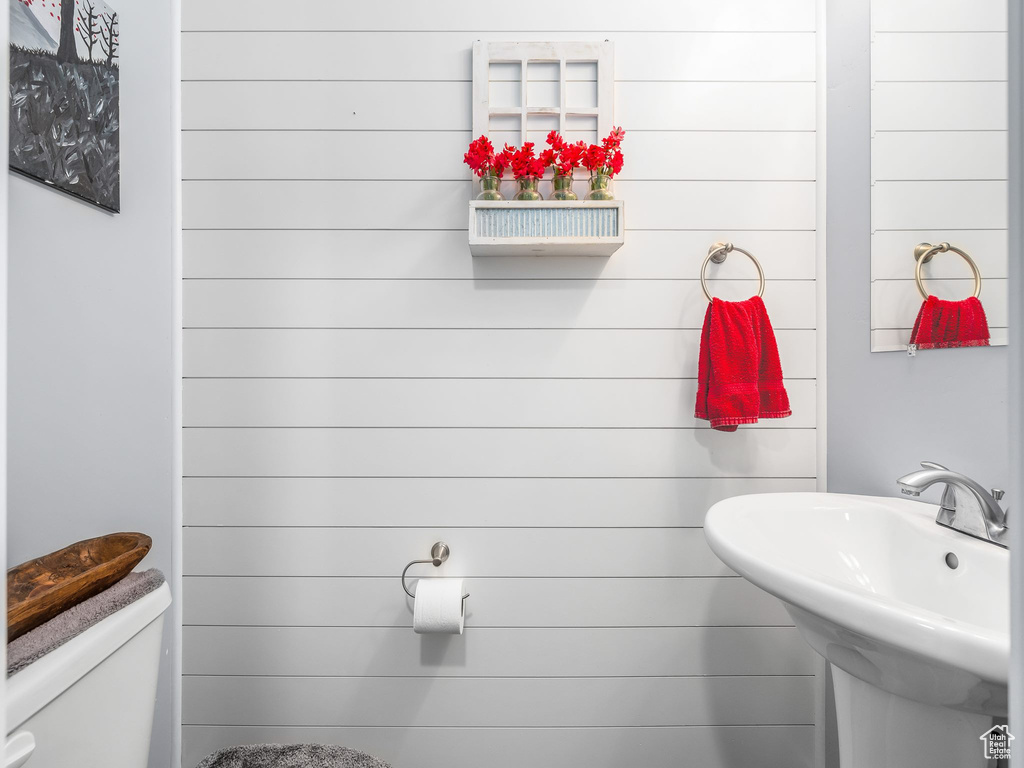 Bathroom featuring sink, wood walls, and toilet