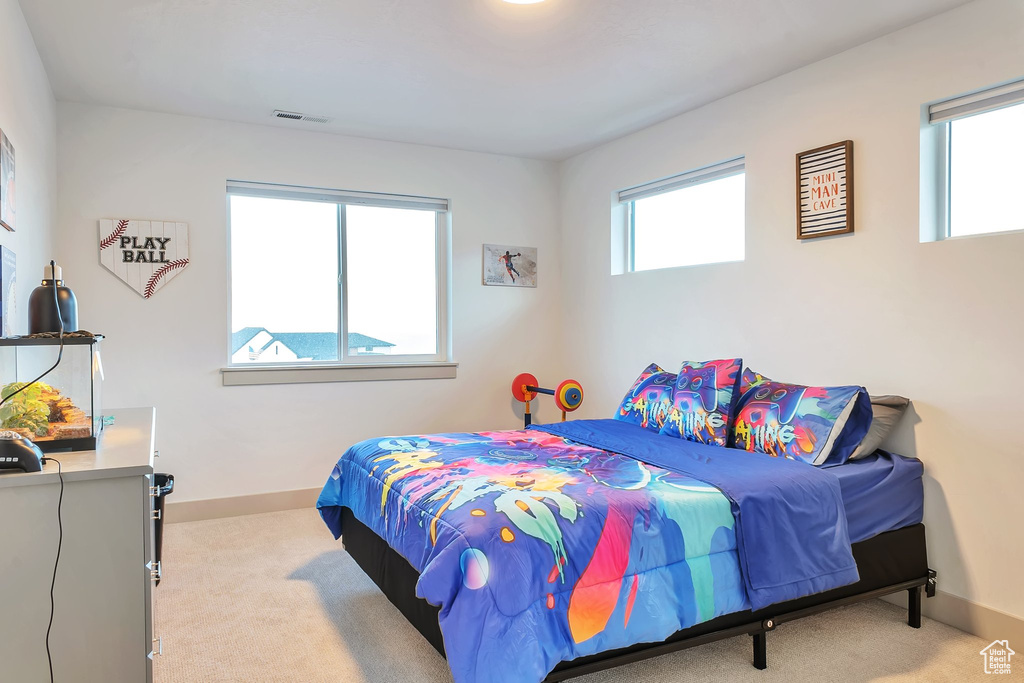 Bedroom featuring light colored carpet and multiple windows