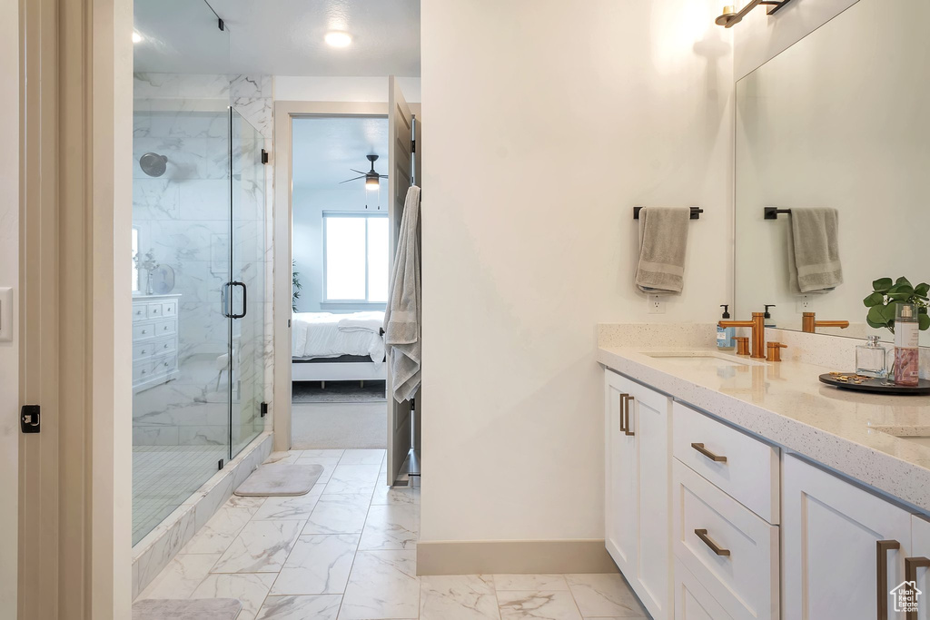 Bathroom featuring vanity, ceiling fan, and a shower with door