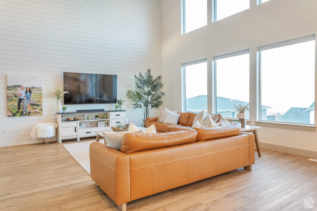 Living room with a towering ceiling and light hardwood / wood-style flooring