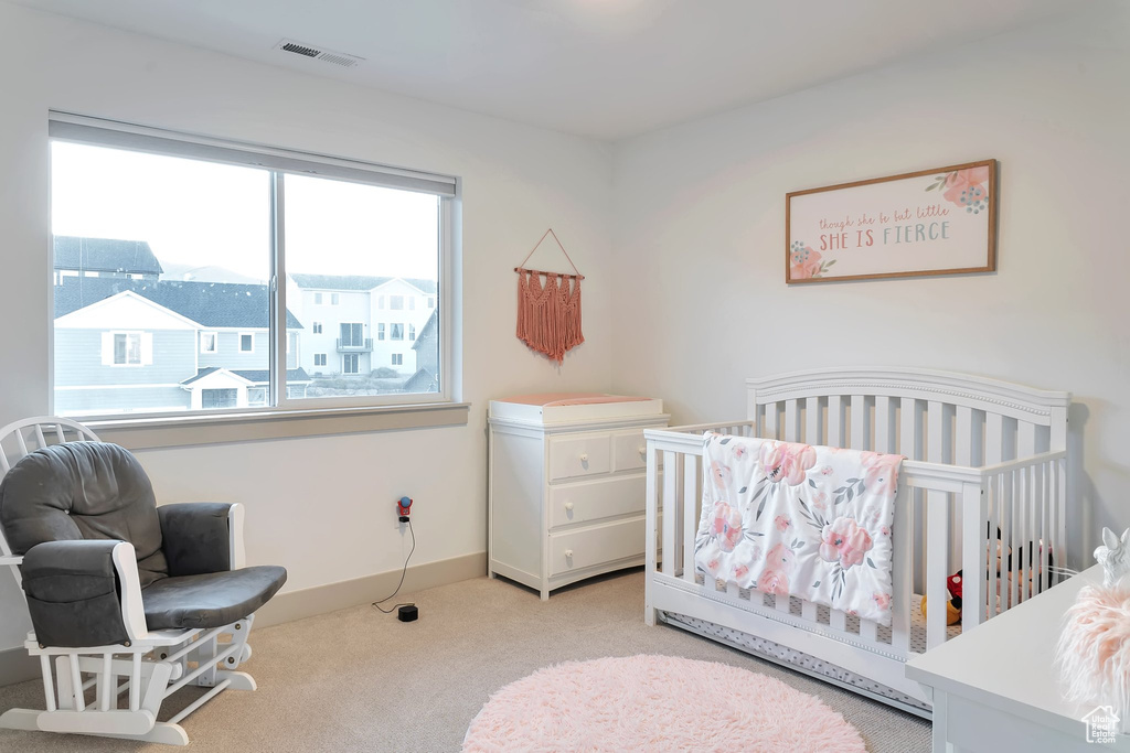 Bedroom featuring light carpet and a nursery area