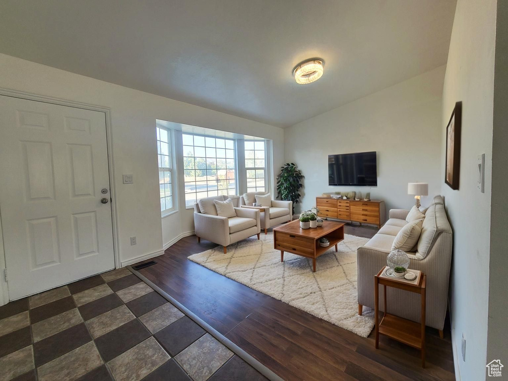 Living room featuring lofted ceiling, dark wood finished floors, and baseboards